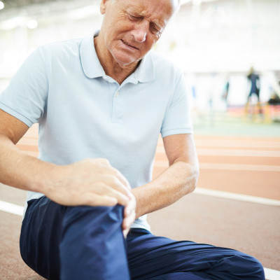older man sitting and holding his painful knee